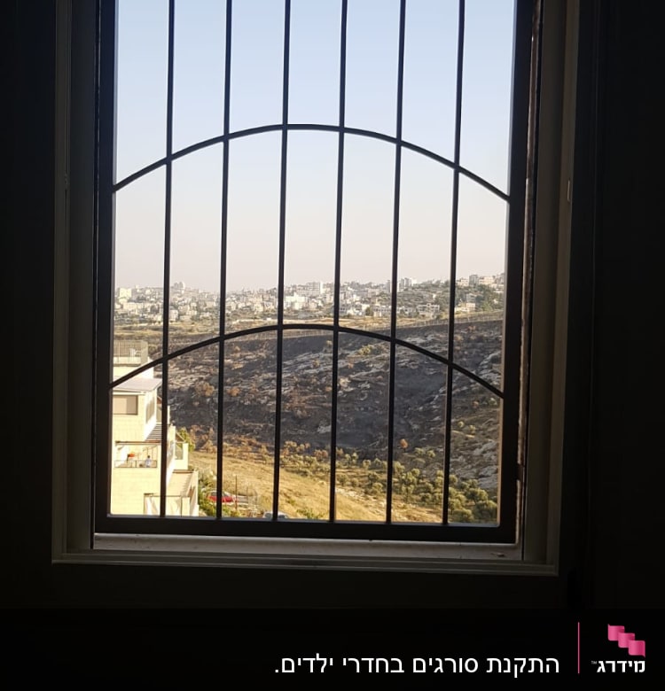 חלון עם סורגים מתכתיים ונוף חיצוני